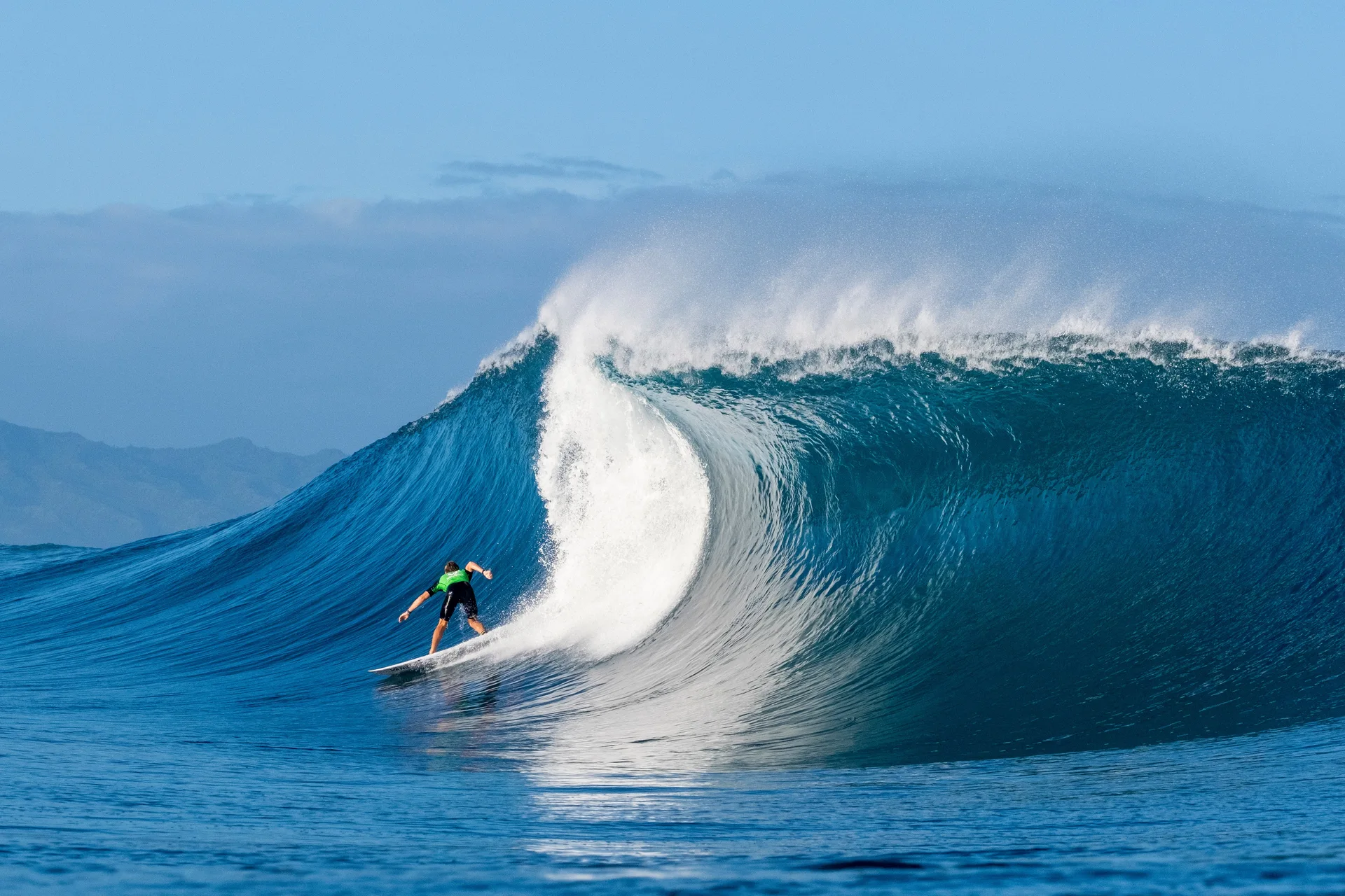 Surfer riding a powerful blue ocean wave